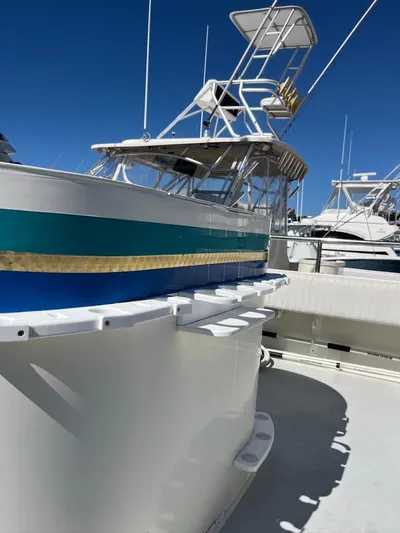  Yacht Photos Pics 1993 Radovich 34 boat with blue stripe, docked under clear blue sky.