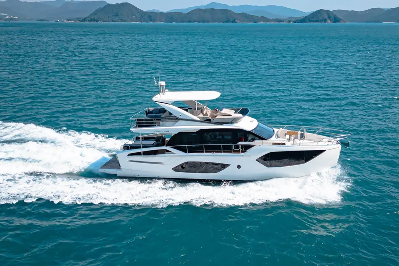  Yacht Photos Pics 2022 Absolute 56 FLY yacht cruising on open sea with scenic mountain backdrop.