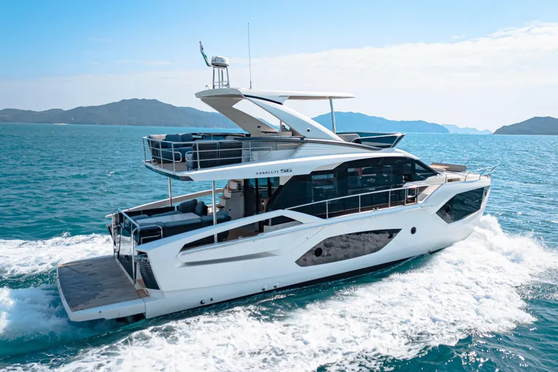  Yacht Photos Pics Luxury 2022 Absolute 56 FLY yacht cruising on open sea with scenic mountain backdrop.