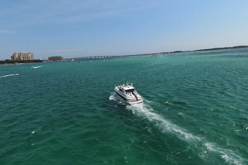  Yacht Photos Pics 2009 Fairline 52 Targa yacht cruising on turquoise waters near a coastal cityscape.