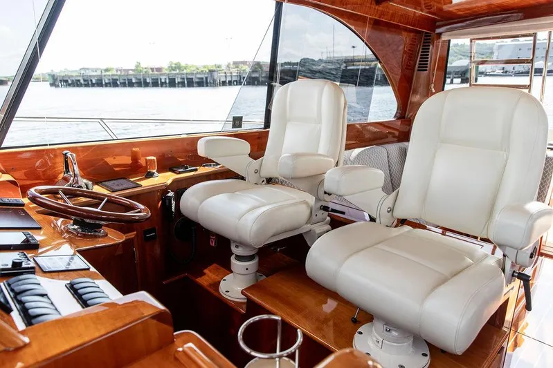 Paddy Wagon Yacht Photos Pics Interior of 2017 Hinckley Talaria 43 Flybridge with luxurious white captain chairs and wooden dashboard.