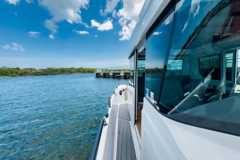  Yacht Photos Pics 2022 Axopar 28 Cabin BRABUS Trim cruising near a scenic dock under a blue sky.