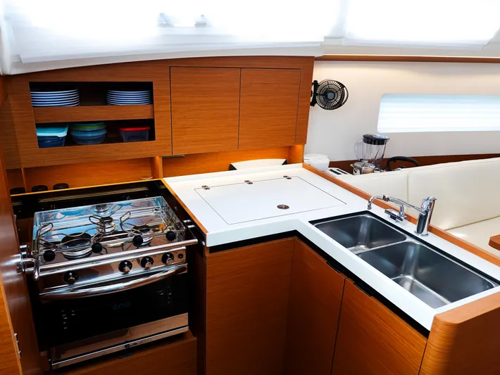 Calypso Express Yacht Photos Pics Modern kitchen in 2024 Jeanneau Sun Odyssey 380 yacht with stove, sink, and wooden cabinetry.