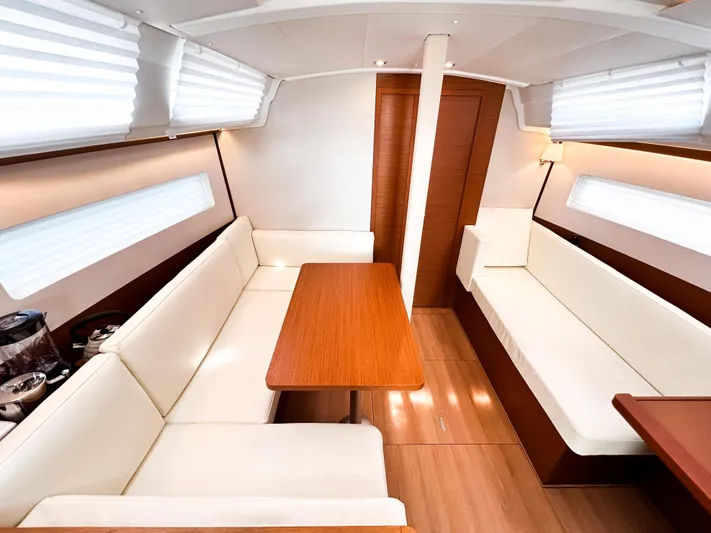 Calypso Express Yacht Photos Pics Interior of 2024 Jeanneau Sun Odyssey 380 sailboat with elegant seating and wooden table.