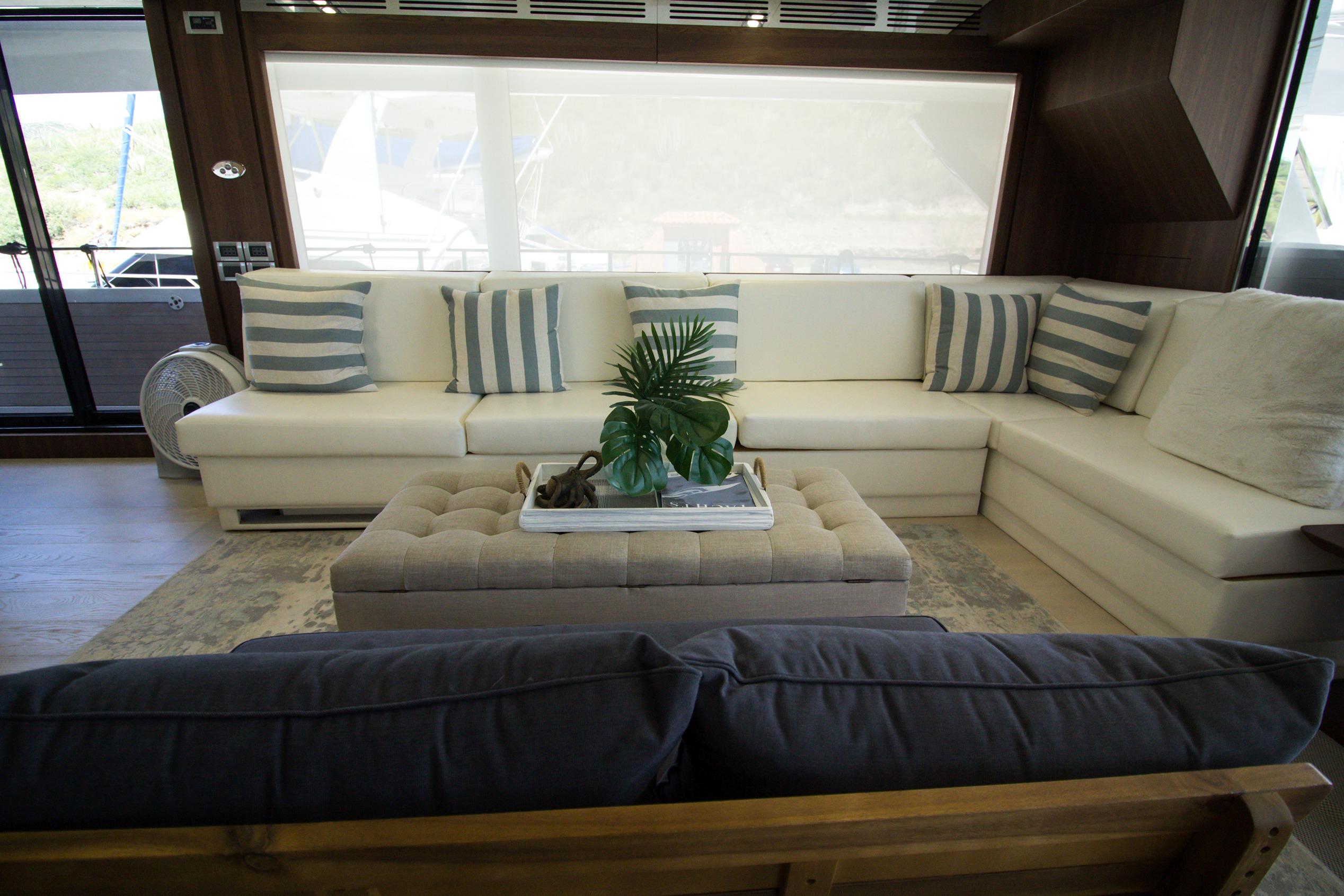 Luxurious interior of 2021 Bugari F86 yacht with white sectional sofa and striped cushions.