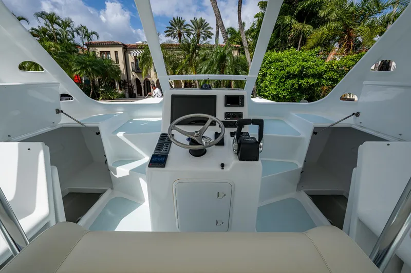  Yacht Photos Pics Cockpit of 2019 Aventura 31 Cat boat with steering wheel and controls, surrounded by lush greenery.