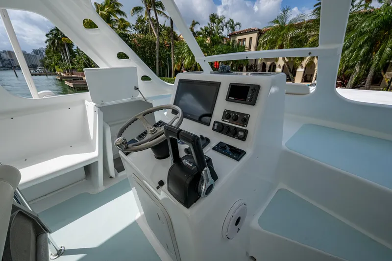  Yacht Photos Pics 2019 Aventura 31 Cat boat cockpit with steering wheel and control panel, surrounded by tropical scenery.