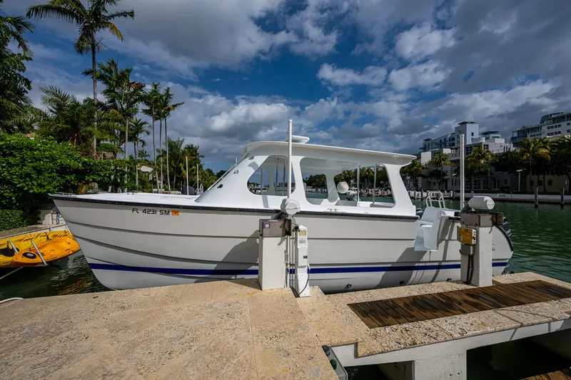  Yacht Photos Pics Aventura 31 Cat 2019 boat docked by palm trees and waterfront buildings.