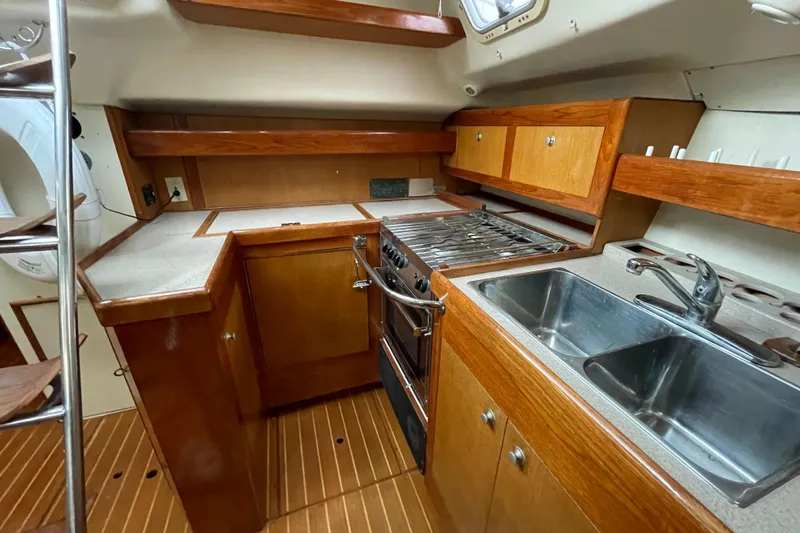  Yacht Photos Pics 1999 Hunter Passage 420 yacht kitchen with wooden cabinets, stove, and dual sink.
