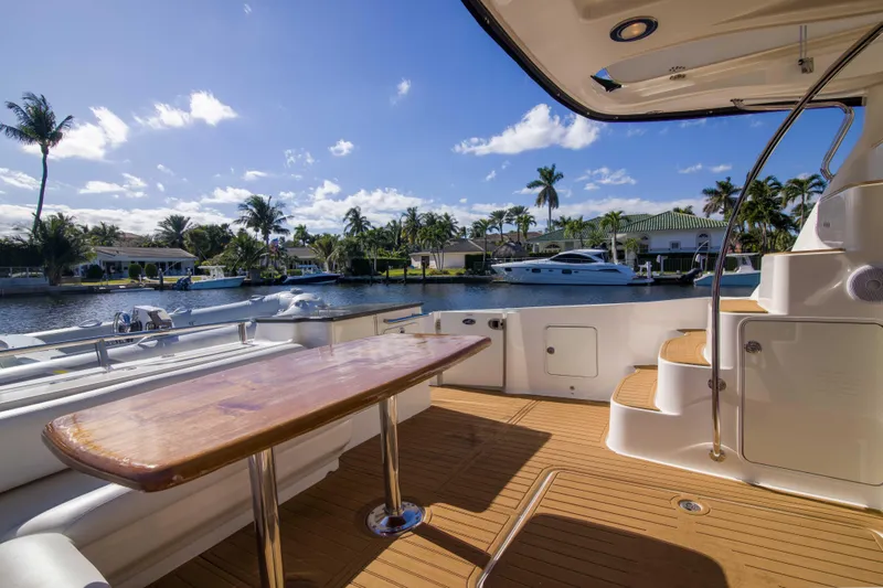Exodus Yacht Photos Pics 2013 Sea Ray 520 Sedan Bridge yacht deck with wooden table, overlooking a scenic waterfront.