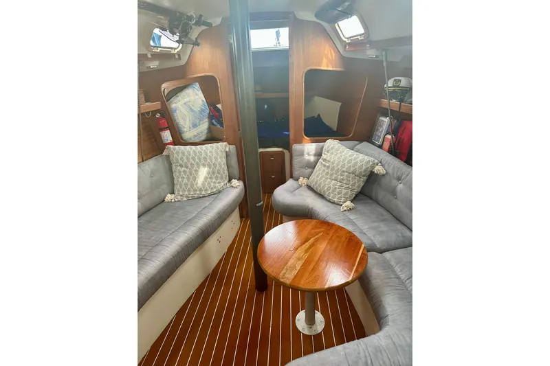 Makai Yacht Photos Pics Interior of a 1999 Catalina 320 sailboat with cozy seating and wooden table.