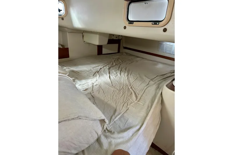 Makai Yacht Photos Pics Cozy cabin interior of 1999 Catalina 320 sailboat with bed and porthole.