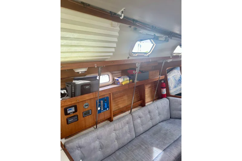 Makai Yacht Photos Pics Interior of a 1999 Catalina 320 sailboat with wooden shelves and a cushioned seating area.