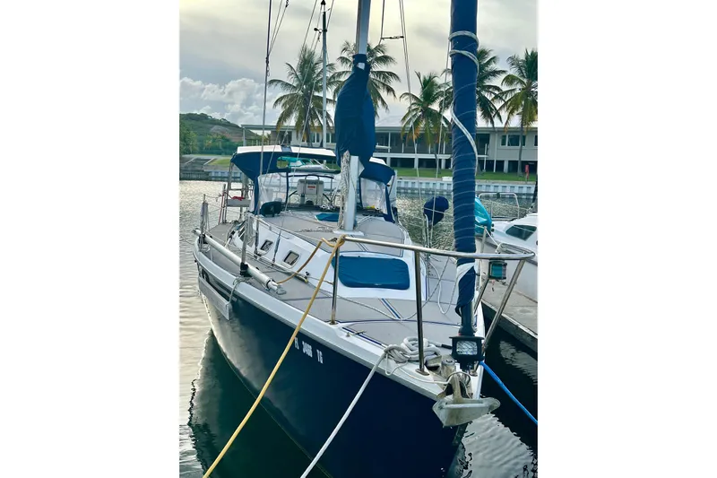 Makai Yacht Photos Pics 1999 Catalina 320 sailboat docked, surrounded by palm trees and calm waters.