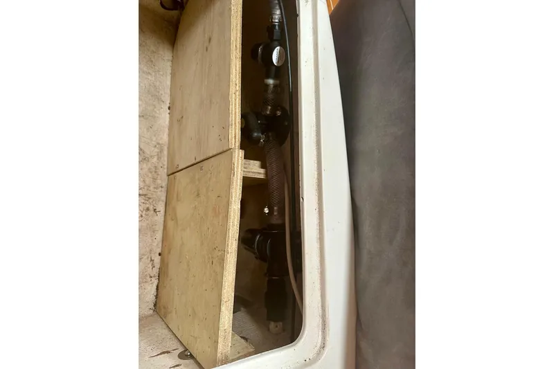 Makai Yacht Photos Pics 1999 Catalina 320 interior compartment with wooden panel and visible plumbing.