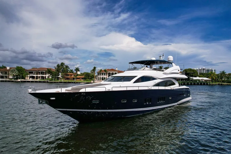 El Tio Yacht Photos Pics 2006 Sunseeker 90 Yacht cruising on a scenic waterway with luxury homes in the background.