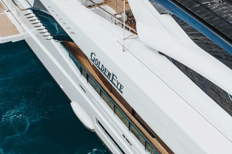 Goldeneye Yacht Photos Pics Mangusta 54 Gransport 2020 yacht "Golden Eye" on blue ocean water, aerial view.