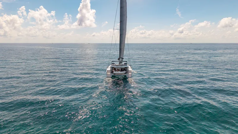 Noble House Yacht Photos Pics Sailing catamaran McConaghy MC60 (2019) on open sea under clear sky.