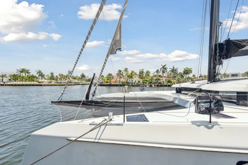 Noble House Yacht Photos Pics 2019 McConaghy MC60 yacht on calm water, with palm trees and houses in the background.
