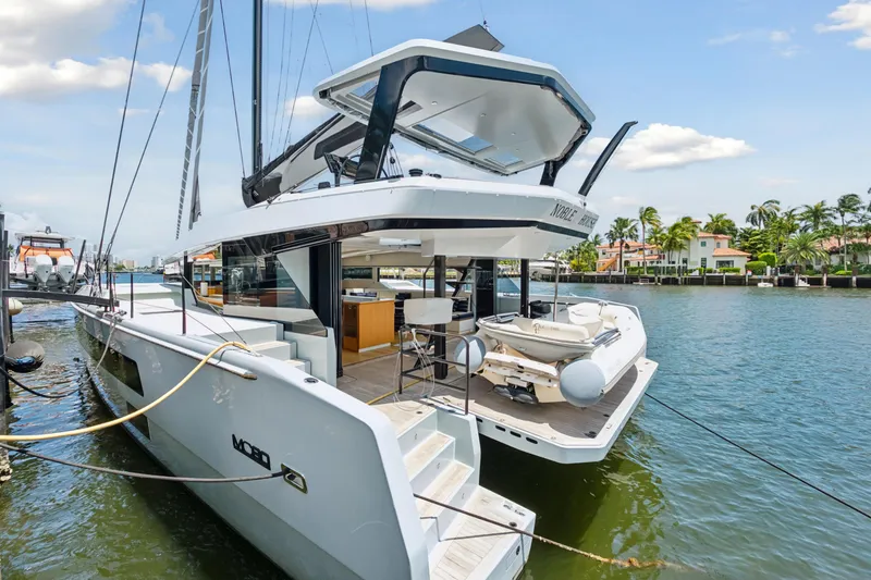 Noble House Yacht Photos Pics 2019 McConaghy MC60 yacht docked by waterfront homes, showcasing sleek design and luxury features.