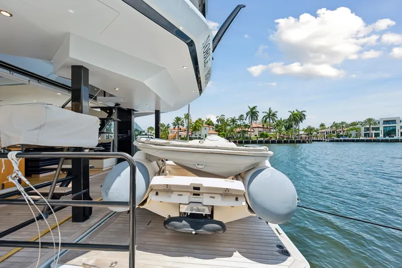 Noble House Yacht Photos Pics 2019 McConaghy MC60 yacht with tender, docked by waterfront homes under a sunny sky.