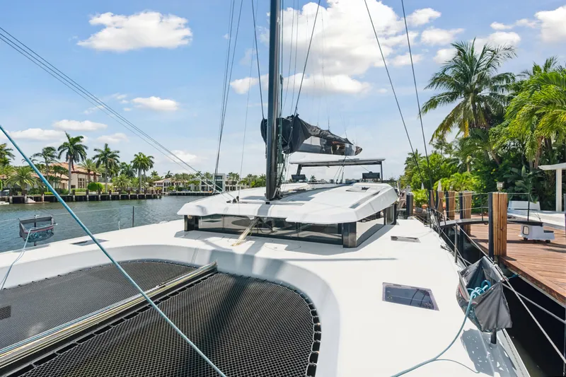 Noble House Yacht Photos Pics 2019 McConaghy MC60 yacht docked by palm trees under a sunny sky.