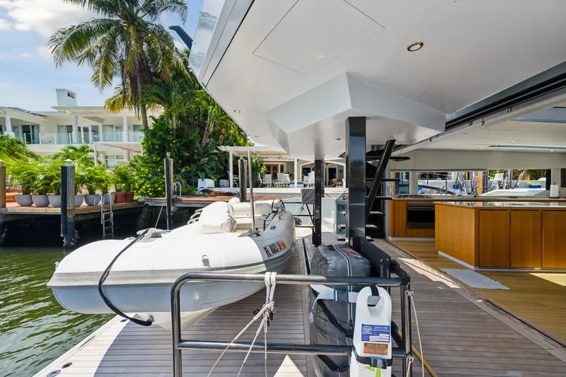 Noble House Yacht Photos Pics 2019 McConaghy MC60 yacht deck with tender, docked near tropical waterfront property.