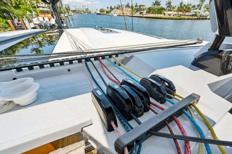 Noble House Yacht Photos Pics 2019 McConaghy MC60 yacht deck with colorful ropes and pulleys, docked by a scenic waterfront.