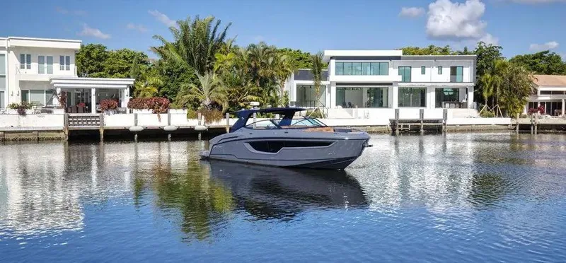  Yacht Photos Pics 2023 Cruisers Yachts 38 GLS on calm water near modern waterfront homes.