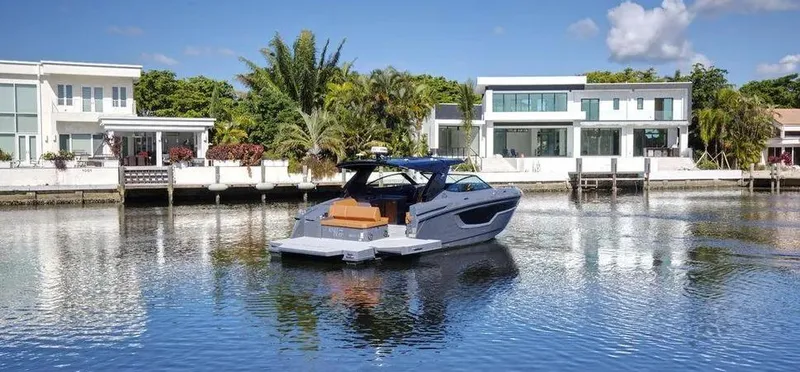  Yacht Photos Pics 2023 Cruisers Yachts 38 GLS on a serene waterfront with modern homes in the background.