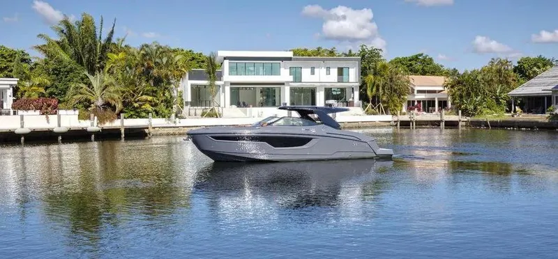  Yacht Photos Pics 2023 Cruisers Yachts 38 GLS on serene water, modern waterfront homes in background.
