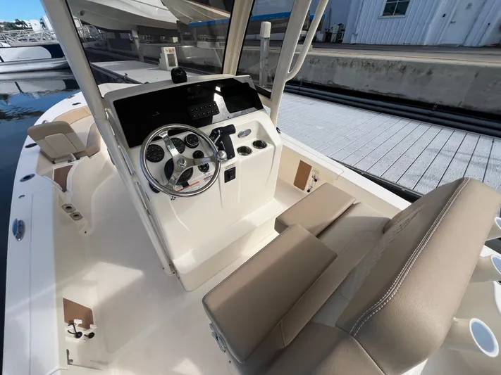  Yacht Photos Pics 2025 Scout 231 XSB boat interior with steering wheel and seating, docked at marina.