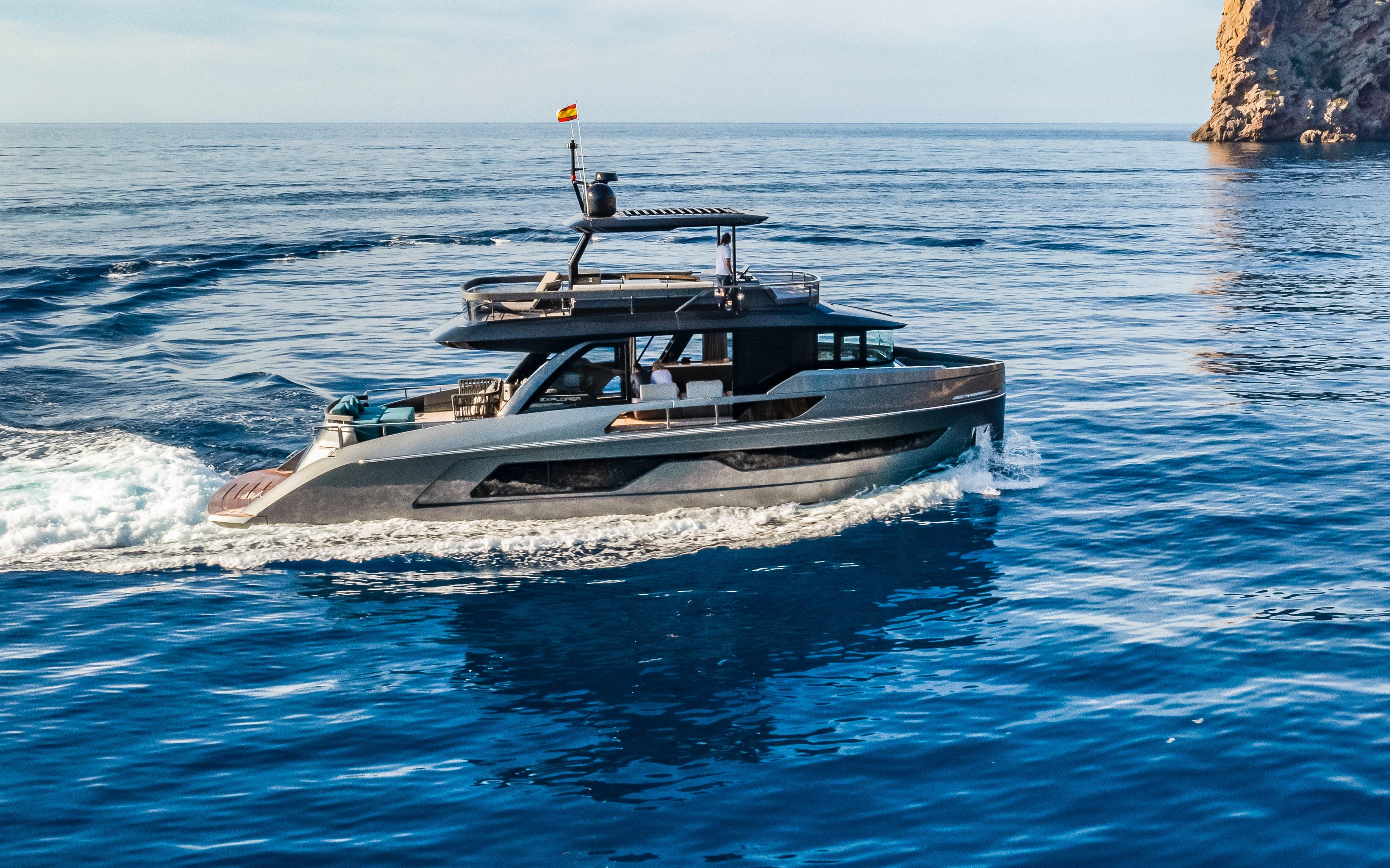 2025 Explorer 62 yacht cruising on open sea near rocky coastline.