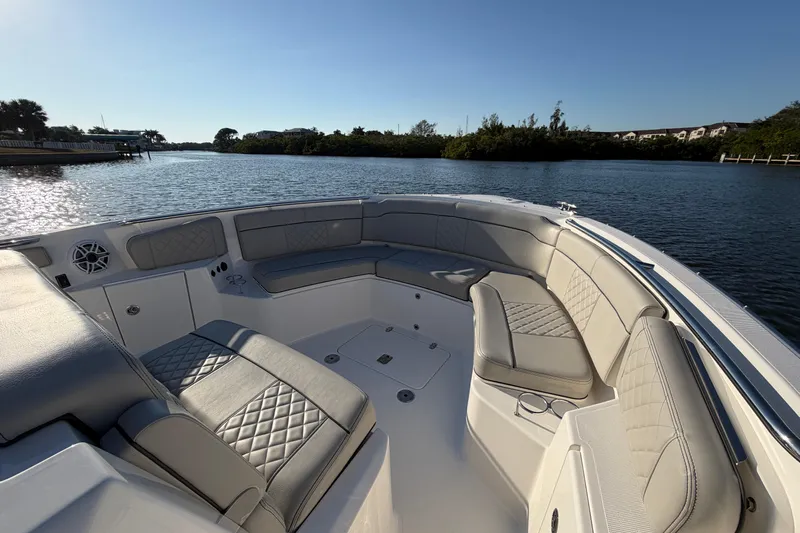  Yacht Photos Pics 2023 Pursuit S 328 Sport boat interior with luxurious seating on a calm waterway.