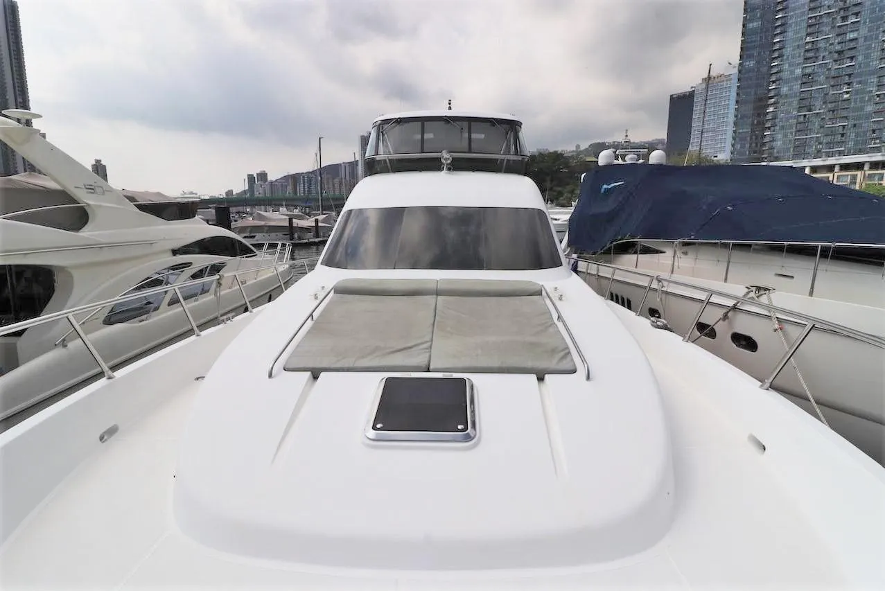 Luxurious 2010 Ruby 65 Feet Yacht docked in a marina with cityscape backdrop.