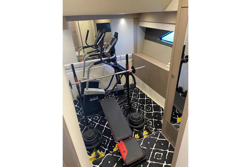  Yacht Photos Pics Home gym setup inside a 2019 Sunseeker Manhattan 66 yacht, featuring exercise equipment.