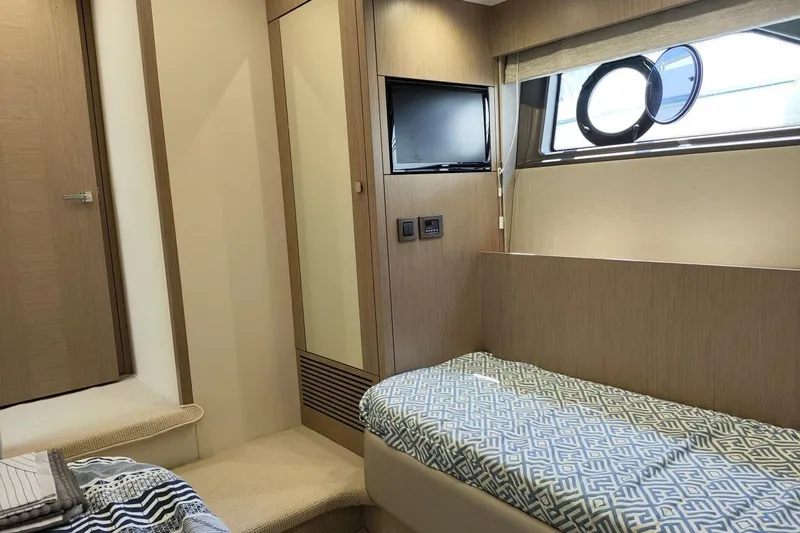  Yacht Photos Pics 2019 Sunseeker Manhattan 66 interior cabin with bed, TV, and porthole window.