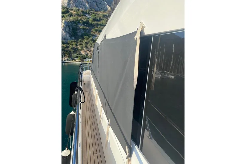  Yacht Photos Pics 2019 Sunseeker Manhattan 66 yacht deck with protective cover, docked near rocky shoreline.