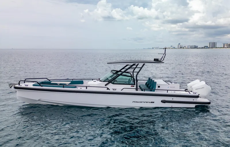  Yacht Photos Pics 2023 Axopar 28 T-Top boat on calm ocean with city skyline in background.