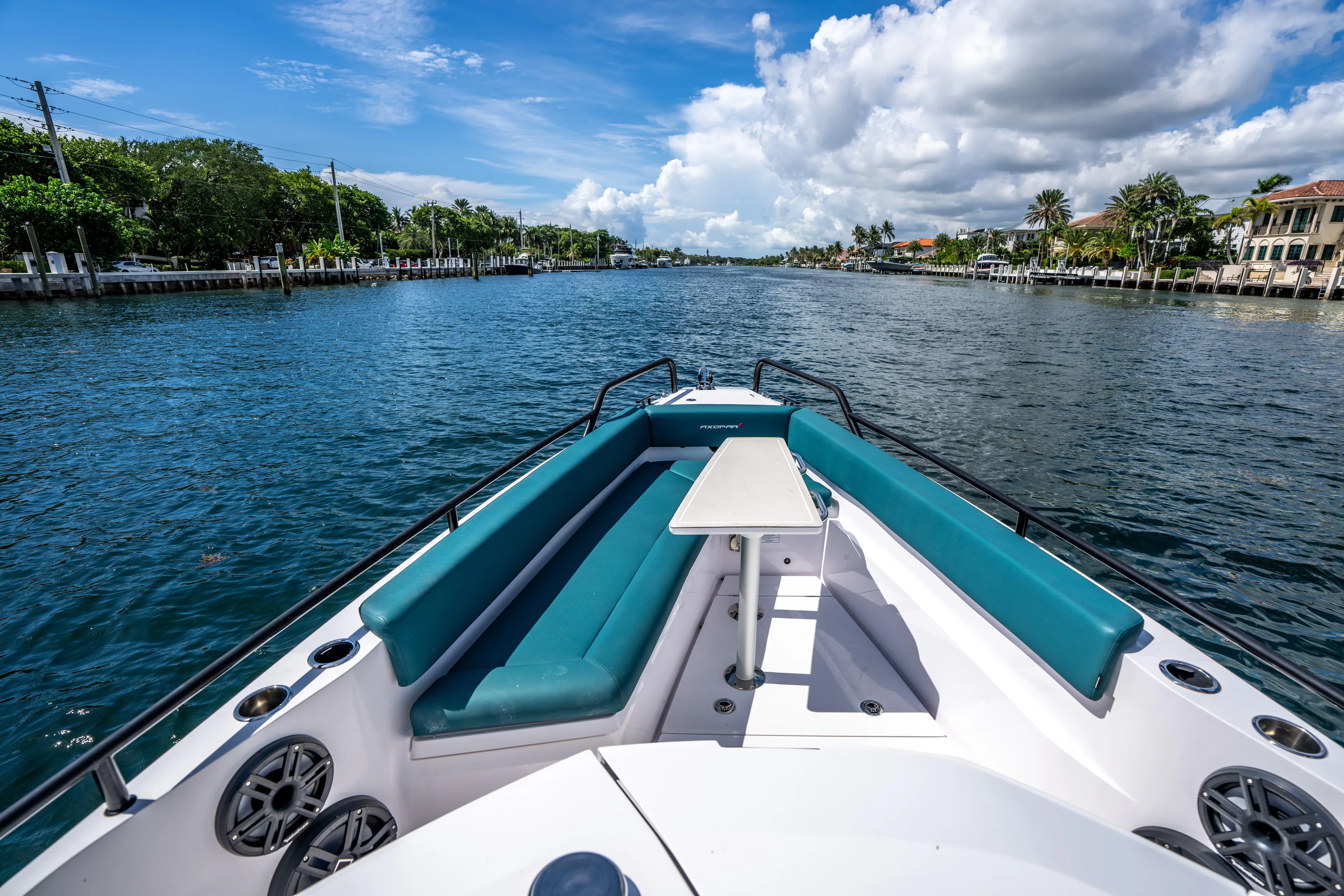  Yacht Photos Pics 2023 Axopar 28 T-Top boat cruising on a scenic waterway under a blue sky.