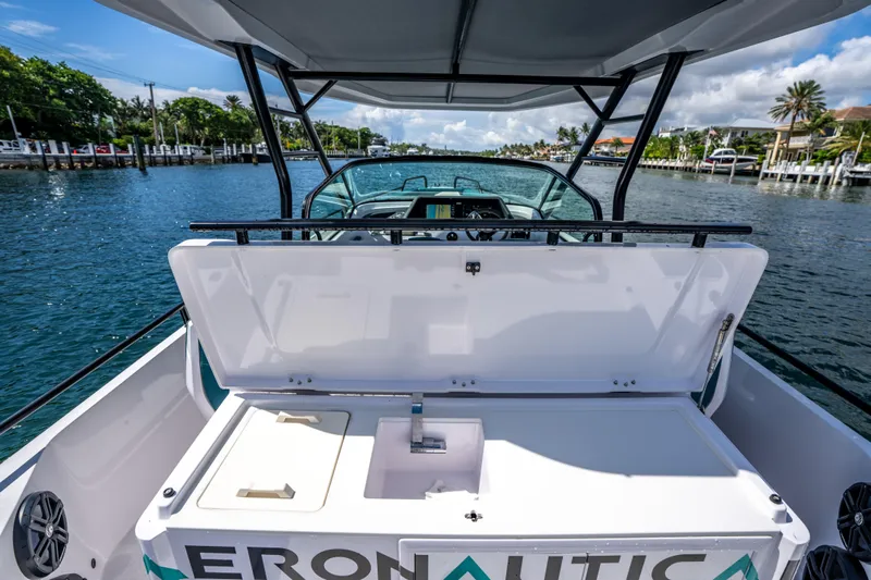  Yacht Photos Pics 2023 Axopar 28 T-Top boat with open storage compartment on a sunny day.