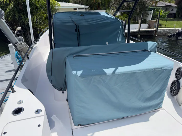  Yacht Photos Pics 2023 Axopar 28 T-Top boat with blue protective covers docked by the water.
