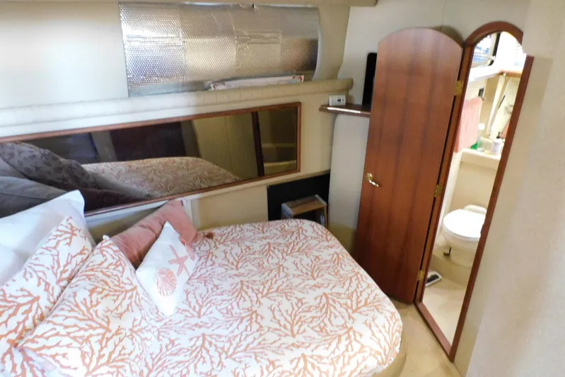 How Lucky Yacht Photos Pics 2003 Cruisers Yachts 3750 Motoryacht bedroom with ensuite bathroom, featuring coral-themed bedding.