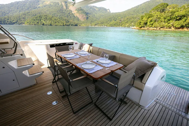Catissa Yacht Photos Pics Luxurious dining area on 2024 Ferretti Yachts 670, overlooking serene waters and lush greenery.