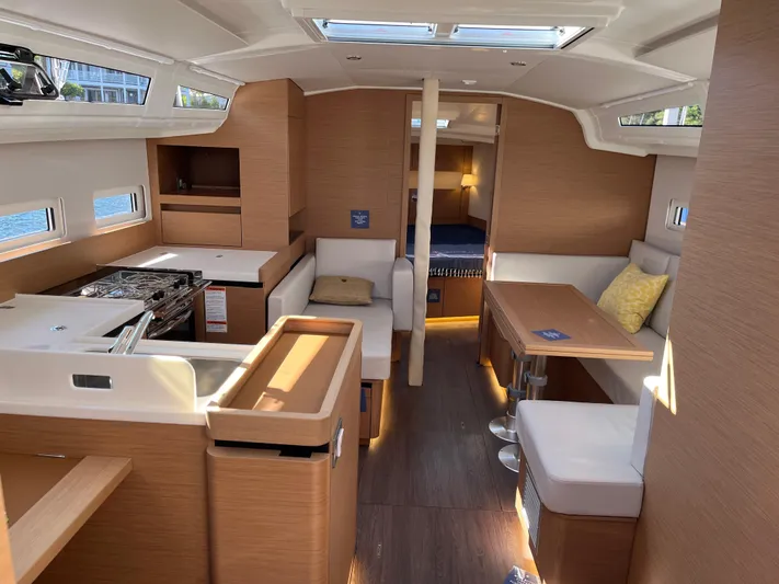  Yacht Photos Pics Interior of 2024 Jeanneau Sun Odyssey 410 sailboat, featuring modern wood finish and cozy seating.