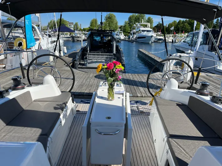  Yacht Photos Pics 2024 Jeanneau Sun Odyssey 410 sailboat interior with dual steering wheels and floral centerpiece.