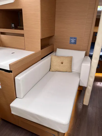  Yacht Photos Pics 2024 Jeanneau Sun Odyssey 410 interior with white cushioned seating and wooden cabinetry.