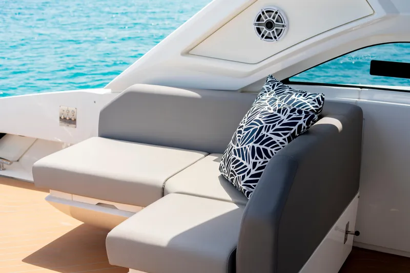  Yacht Photos Pics Luxurious seating on 2024 Sunseeker Superhawk 55 yacht with decorative pillow, ocean backdrop.