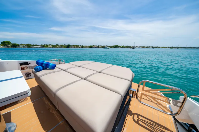  Yacht Photos Pics Luxurious Sunseeker Superhawk 55 yacht deck with sunbed, 2024 model, overlooking serene blue waters.