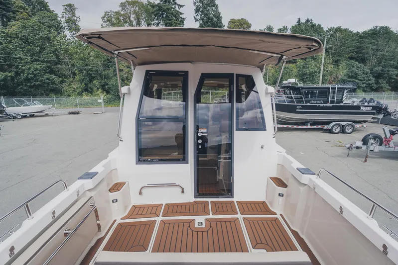  Yacht Photos Pics 2025 Ranger Tugs R-23 boat with teak deck, docked outdoors, showcasing rear view and canopy.